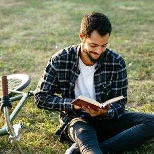 128288849-attractive-smiling-bearded-man-reading-interesting-book-spending-time-with-pleasure-while-sitting-on